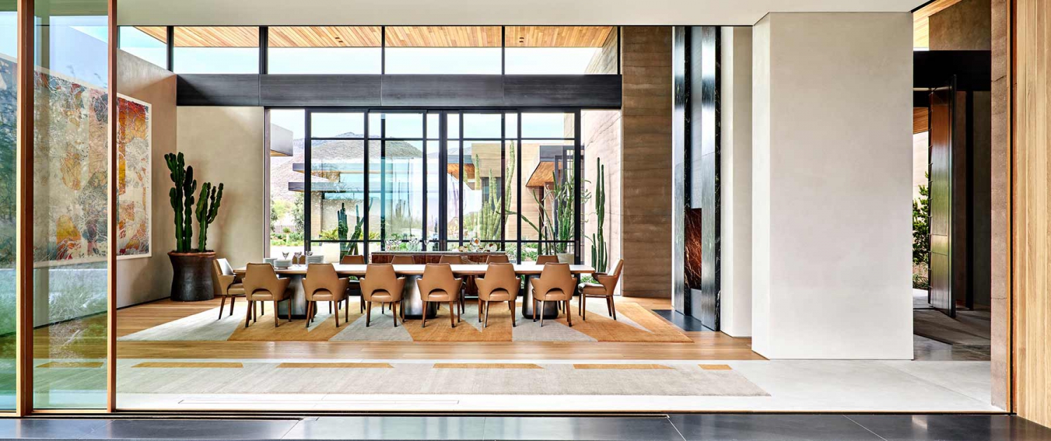 Contemporary, organic dining room on a grand scale, with a handwoven rug and rammed earth construction.